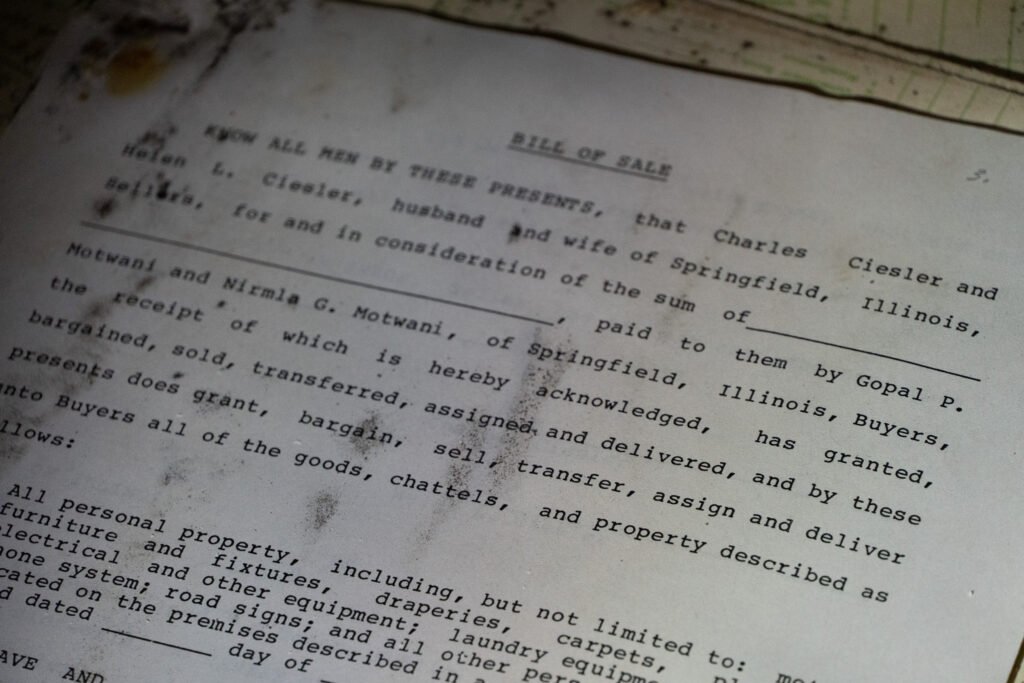 Close-up of a weathered bill of sale document discovered at the abandoned Port of the Islands Hotel in Naples, FL, prior to its demolition. The document records a transaction between Charles and Helen L. Ciesler and Gopal P. Motwani and Nirmia G. Motwani. Partially obscured by stains and dirt, it highlights the decay and historical significance of the site.